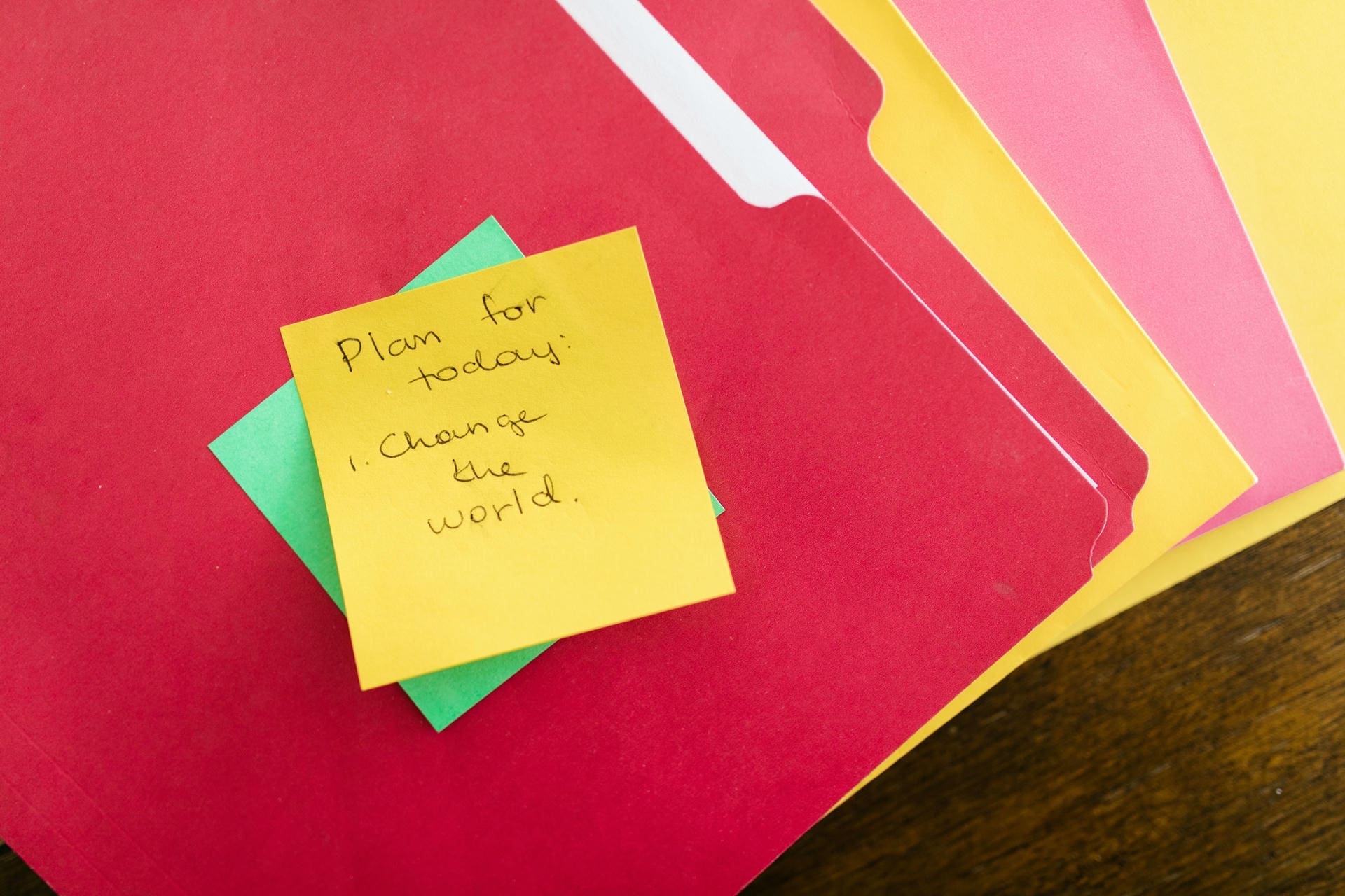 Sticky note on colorful folders reading plan for today change the world representing learning beliefs in education that go beyond slogans