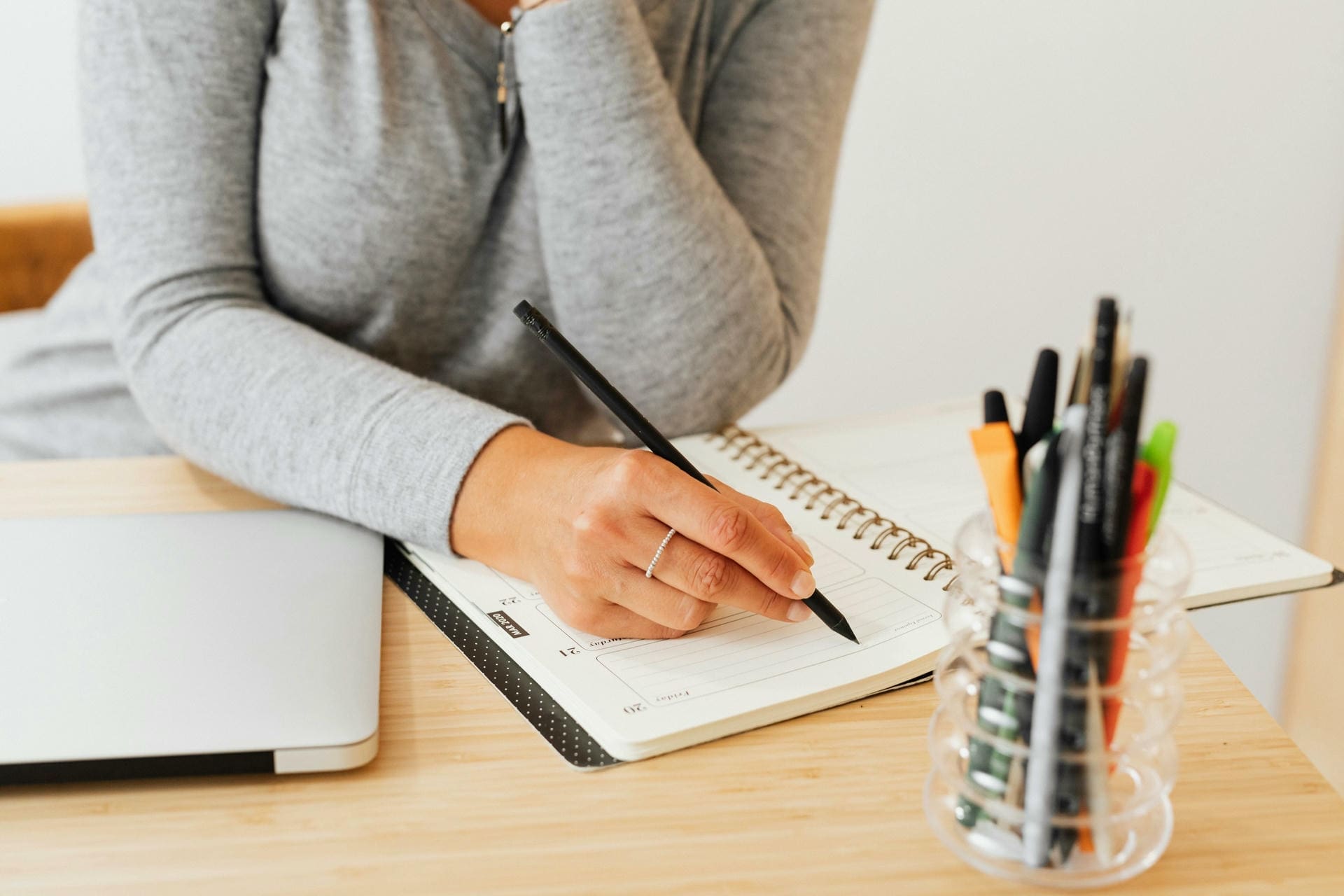 Educator writing in a notebook while reflecting on school improvement planning and learning beliefs